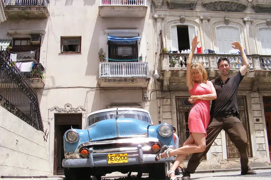 Una pareja baila junto a un almendrón en una calle de La Habana Vieja